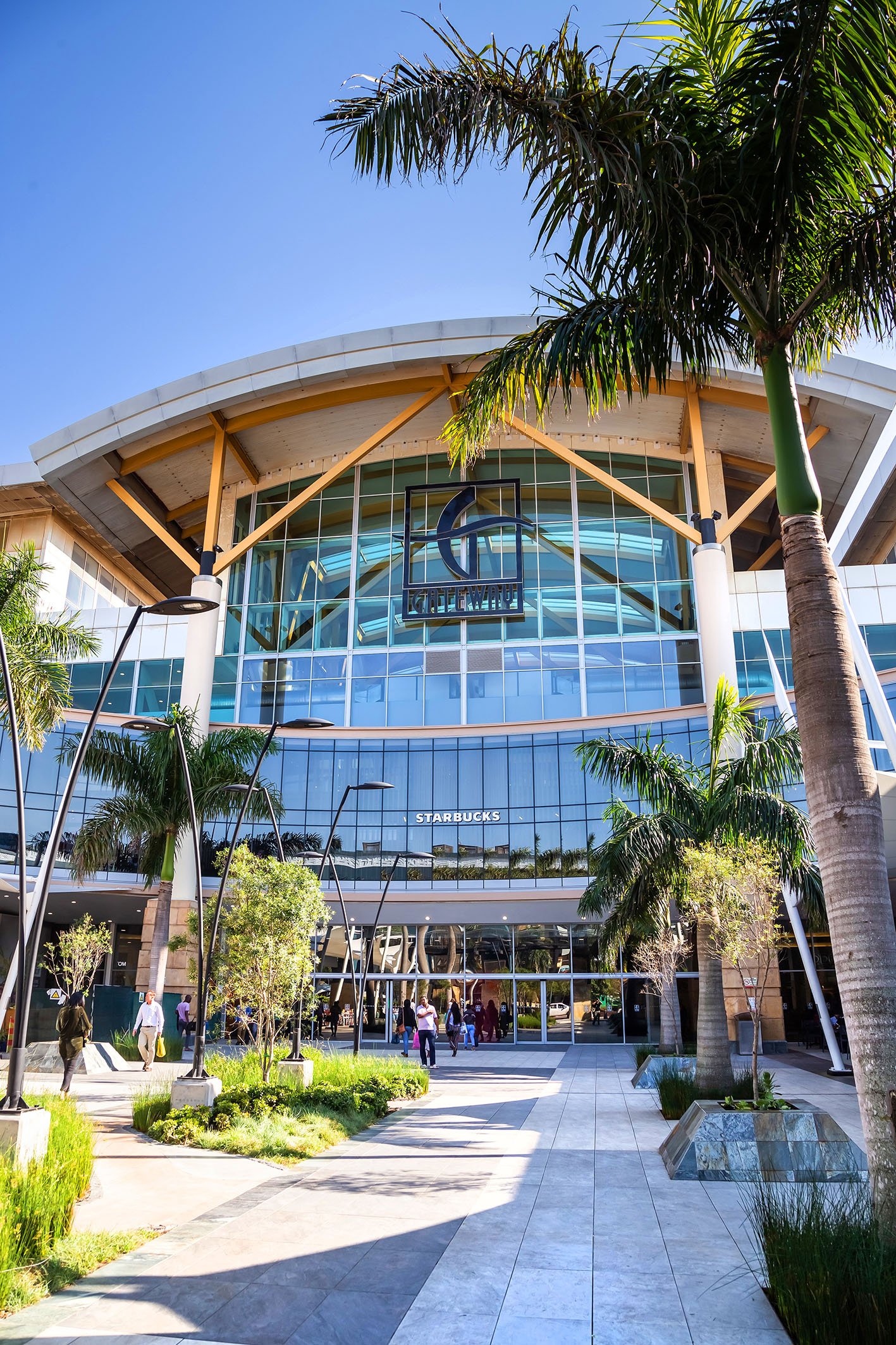 Durban, South Africa, 15th May - 2019: Exterior of shopping complex with glass facade and palm trees.